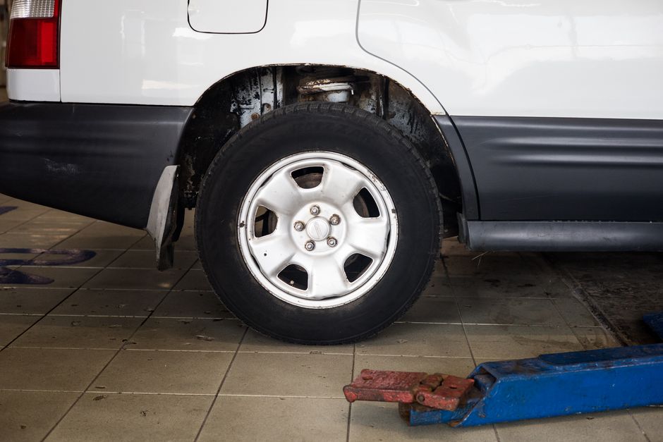 Detailed view of a car wheel in an auto repair shop setting with a hydraulic jack.